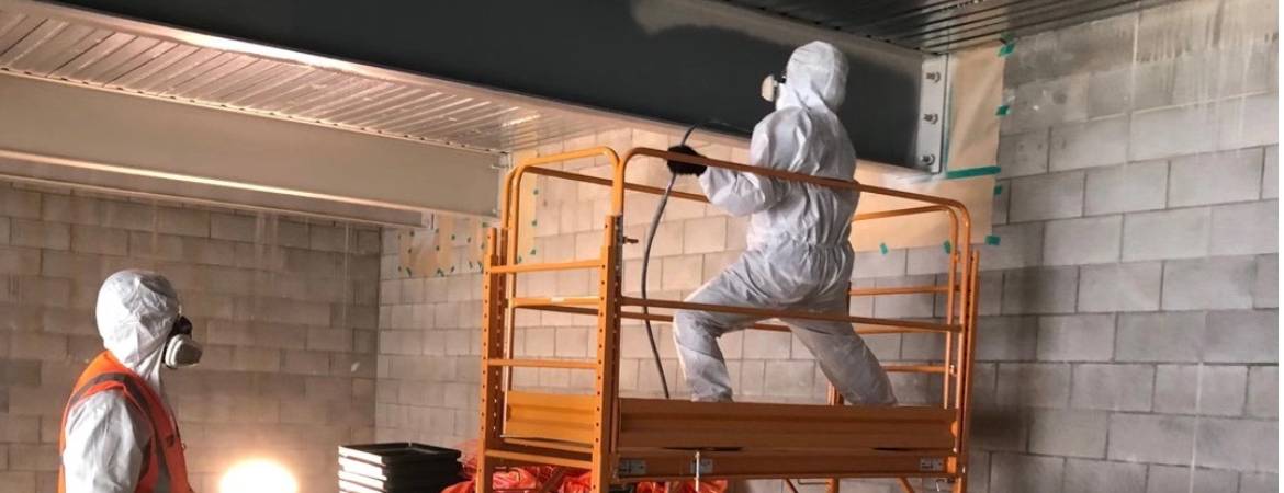 Intumescent paint coating in progress, with workers on scissor lift in protective gear